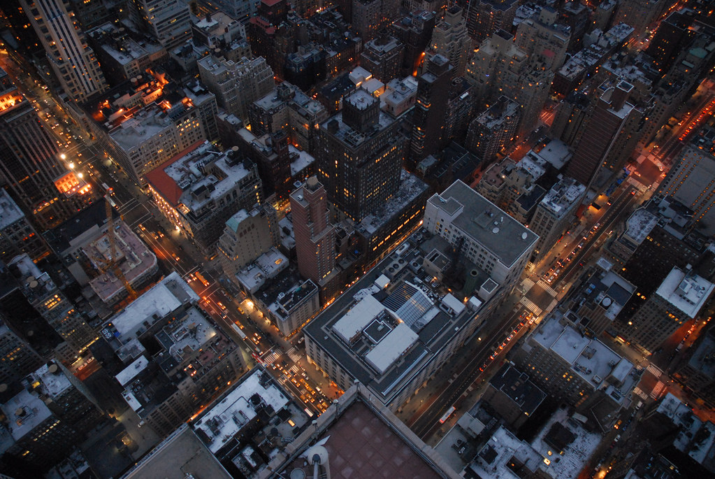 Manhattan's street grid seen from high above at dusk, lit streets between dark blocks